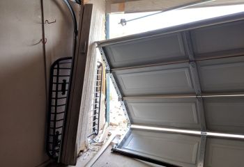 Garage door dislodged from tracks with visible damage after a collision in Champlin, MN