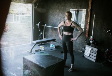 Woman standing in a well-organized private garage gym with custom storage in Champlin, MN