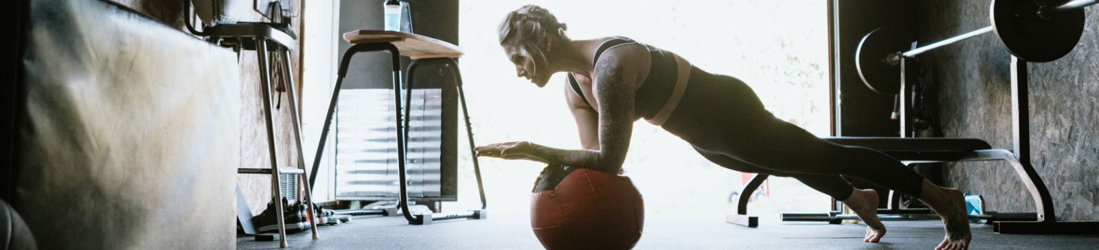 Person exercising on a medicine ball in a well-equipped garage gym with workout equipment in Champlin, MN